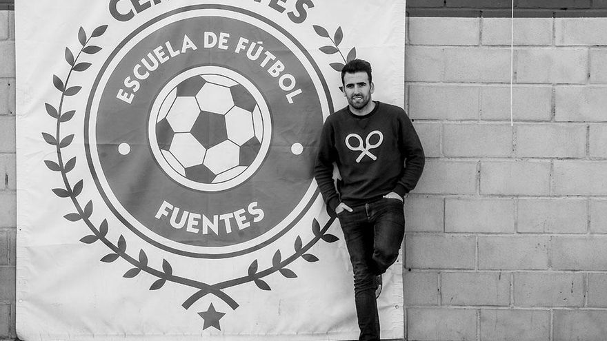 Juan Rafael Fuentes junto al escudo de la escuela